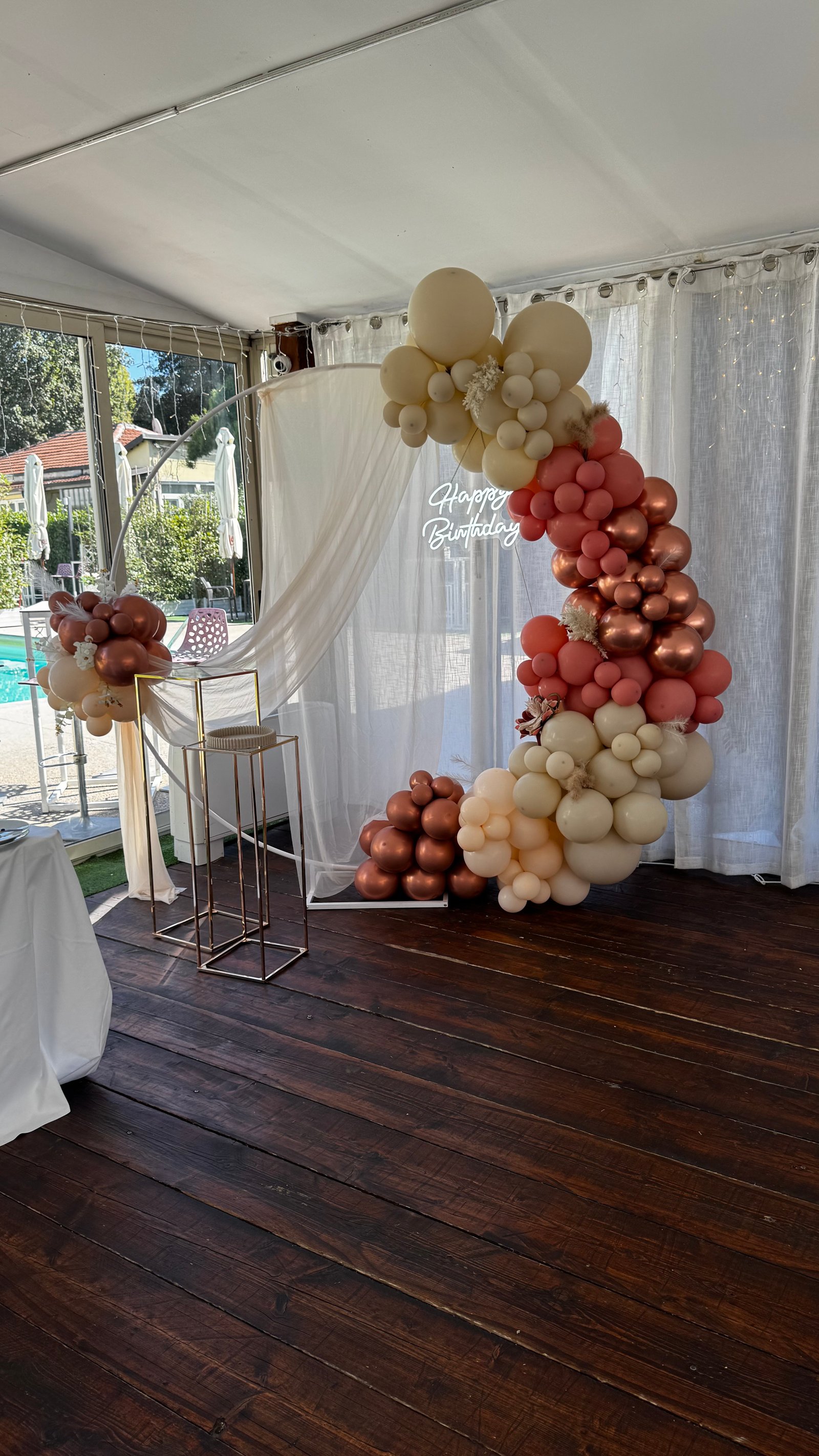 Arco circolare con palloncini rosa antico, crema e rose gold con drappeggi e neon Happy Birthday