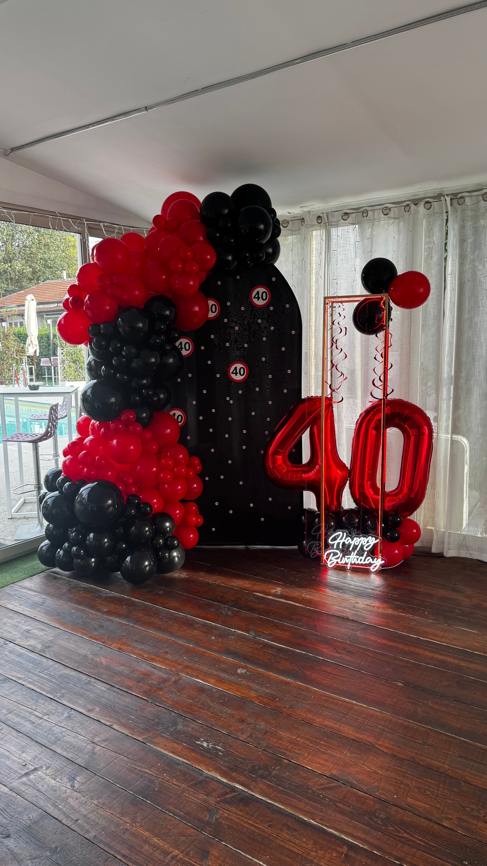 40esimo compleanno con palloncini rossi e neri, fondale nero e numeri foil 40 rossi