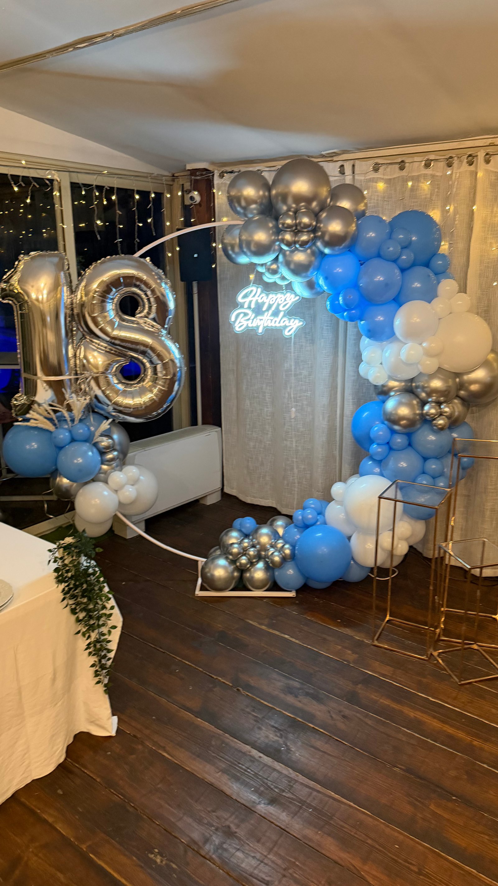 18esimo compleanno con arco palloncini blu, argento e bianchi, numeri foil 18 e neon Happy Birthday