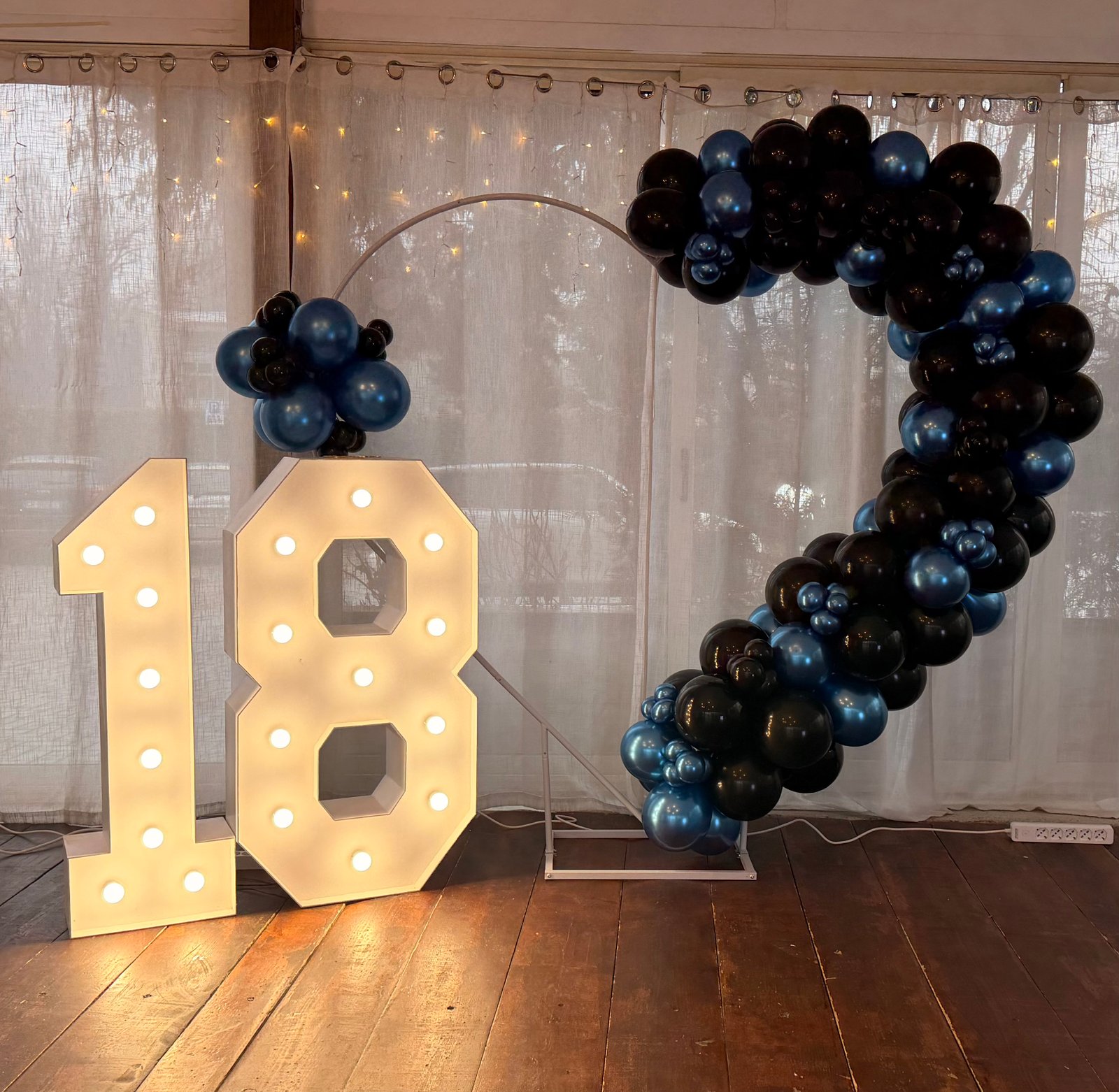 18esimo compleanno con numeri luminosi 18 e arco di palloncini blu navy e neri